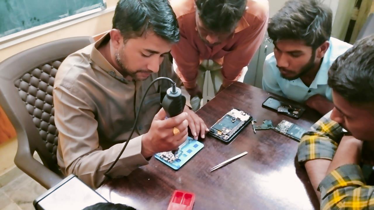 Young men learning mobile phone repair