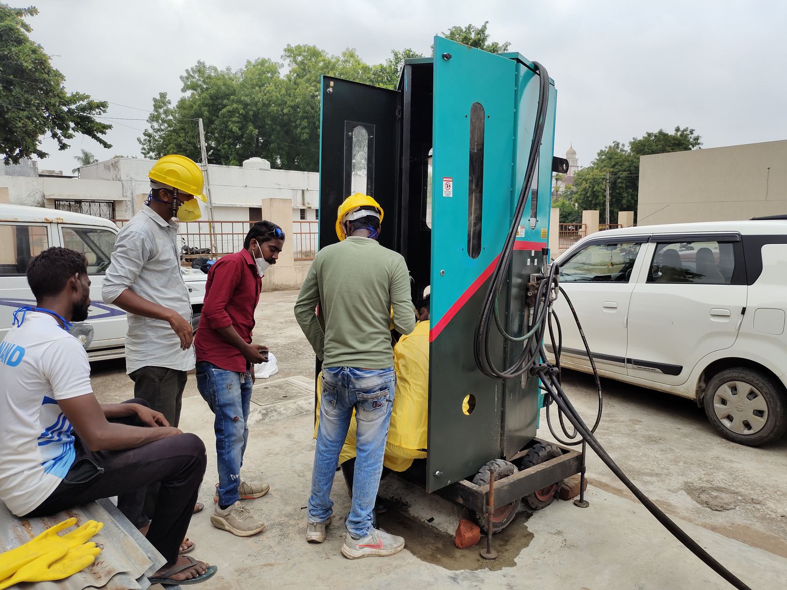 Workers in helmets with a sewer-cleaning machine