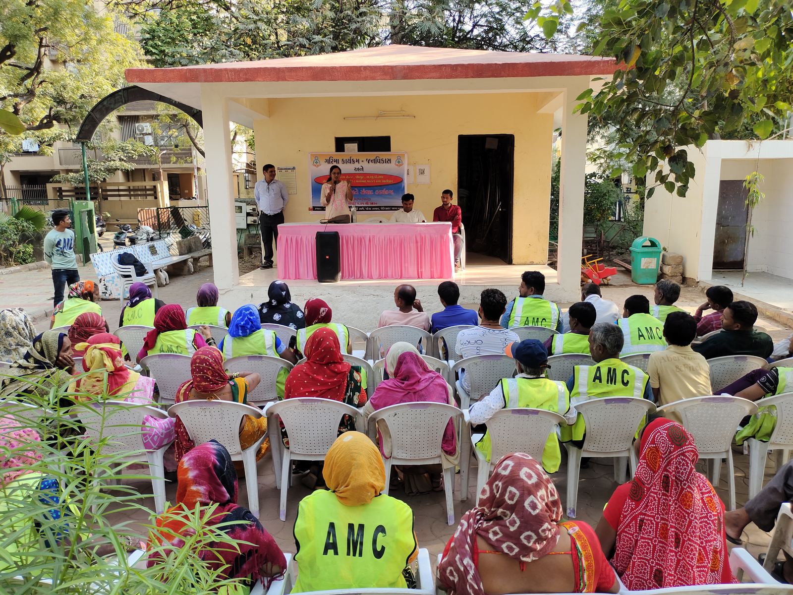 Sanitation workers in safety vests at an awareness meeting